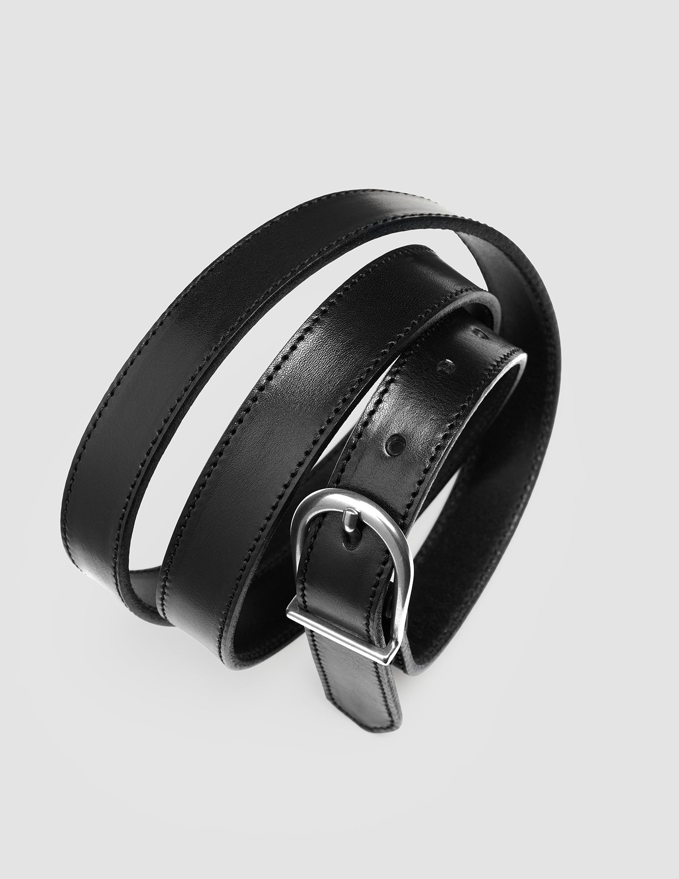 Ett spiralfört, smalt läderbälte för damer i silver och svart med en slank skandinavisk design.